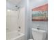 White tub-shower combination and toilet accented with a colorful painting at 1221 Tidewater Dr. # 2811, North Myrtle Beach, SC 29582