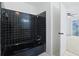 A bathtub with black tiles and an entrance to the bedroom with an installed ceiling fan at 1590 Landing Rd., Myrtle Beach, SC 29577
