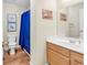Bathroom featuring a single sink vanity, framed artwork, and a tub shower with a blue curtain at 17 South Oak Dr., Surfside Beach, SC 29575