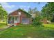 Brick home with a covered porch and overgrown vegetation, presenting renovation opportunities at 1895 Bucksville Dr., Conway, SC 29527