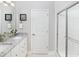 Bright bathroom featuring double sinks, granite countertop, white cabinets, and a glass-enclosed shower at 2429 Watershed Way, Longs, SC 29568