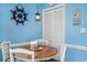 Cozy dining area with a round wooden table, white chairs, and charming nautical decor at 3700 Golf Colony Lane # 6J, Little River, SC 29566