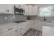 Updated kitchen features white cabinets, stainless steel appliances, gray backsplash, and wood-look floors at 395 Dunbarton Ln., Conway, SC 29526