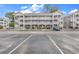 Three-story condo building featuring private balconies, well-kept landscaping, and ample parking at 4787 Wild Iris Dr. # 303, Myrtle Beach, SC 29577