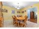 Bright dining room with a round wooden table, six chairs, and decorative wall shelves with yellow walls and light tile flooring at 4818 Harvest Dr., Myrtle Beach, SC 29579
