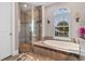 Bright bathroom with soaking tub, glass shower, and arched window providing natural light and backyard views at 7253 Seville Dr., Myrtle Beach, SC 29572