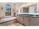 Primary bathroom offers double vanities, soaking tub, and large window providing natural light and views at 7253 Seville Dr., Myrtle Beach, SC 29572