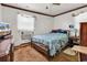 Modest bedroom features a floral comforter, window AC, and vintage furniture on a carpeted floor at 1104 Ragin St., Myrtle Beach, SC 29577