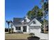 Charming white home featuring a modern roofline, an attached two-car garage, and professionally landscaped yard at 1142 Fiddlehead Way, Myrtle Beach, SC 29579