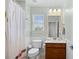 Clean bathroom with wainscoting, a shower with a patterned curtain, a wood vanity, and a well-lit mirror at 1444 Thames Ct., Myrtle Beach, SC 29577
