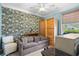 Bright bedroom featuring a patterned accent wall, ceiling fan, comfortable sofa, and natural light from the window at 1444 Thames Ct., Myrtle Beach, SC 29577