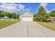 Detached garage with a wide driveway and a clean, white garage door, set against a backdrop of trees at 1566 Bessent Ave., Little River, SC 29566