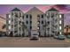 Attractive condo building with multiple floors, exterior staircases, and ample parking at dusk at 189 Ella Kinley Circle # 201, Myrtle Beach, SC 29588