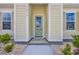 Welcoming pale green front door with glass panes and sidelights, and manicured front yard at 1936 Indigo Cove Ln, Calabash, NC 28467