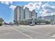 Multi-story building with a unique architectural design, palm trees, and street view, under a partly cloudy sky at 2401 S Ocean Blvd. # 351, Myrtle Beach, SC 29577