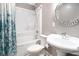 Bathroom with shower-tub combo and floral shower curtain, round mirror, and pedestal sink at 299 Lake Arrowhead Rd., Myrtle Beach, SC 29572