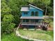 Two-story blue home with metal roof surrounded by lush greenery and a stone-lined landscape at 329 Kaufman St., Georgetown, SC 29440