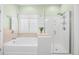 Bathroom with a soaking tub, glass-enclosed shower, and neutral-toned tile at 4 Stillwater Ct., Murrells Inlet, SC 29576