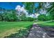 A lush green backyard and walking path leading towards a beautiful home nestled among mature trees at 4294 Rivergate Ln., Little River, SC 29566