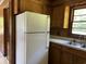 Classic kitchen view highlighting a white refrigerator, wood cabinets, and a double basin sink at 444 Davis Rd., Hemingway, SC 29554