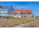 Elevated beach house with a red roof, screened porch, and scenic ocean views at 4803 Bucks Bluff Dr., North Myrtle Beach, SC 29582