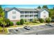 Wide angle exterior of condo building featuring a well-kept lawn and ample parking spaces at 4811 Innisbrook Ct. # 306, Myrtle Beach, SC 29579