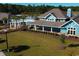 Aerial view of a blue clubhouse with a pergola, green lawn, and lake in the background at 4861 Hopespring St., Myrtle Beach, SC 29579