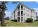 Three-story condo building with screened-in decks, lush greenery, and golf course views at 488 River Oaks Dr. # 61N, Myrtle Beach, SC 29579
