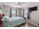 Bright bedroom with ceiling fan, a television, light walls, and blue quilt, complemented by two windows with natural light at 6001-1454 S Kings Hwy., Myrtle Beach, SC 29575