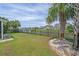 Spacious backyard with lush green grass, black iron fence, palm tree, and view of the waterfront homes at 691 Sandberg St., Surfside Beach, SC 29575