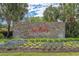 Stone sign for Surfside Beach Club with vibrant flowers and palm trees creating a welcoming entrance at 691 Sandberg St., Surfside Beach, SC 29575