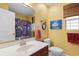 Bright yellow bathroom featuring a large mirror, vanity with sink, toilet, and decorative blue artwork at 696 Rambler Ct., Myrtle Beach, SC 29588