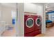 Bright laundry room features red washer and dryer with additional storage and bathroom access at 901 Southwind Ct., Garden City Beach, SC 29576