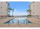 Inviting pool area with lounge chairs, palm trees, and ocean views creating a serene outdoor space at 1310 N Waccamaw Dr. # 204, Garden City Beach, SC 29576
