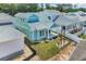 Beautiful two-story light blue beach home with manicured lawn, covered porch, and decorative rock features at 1961 Indigo Cove Ln, Calabash, NC 28467