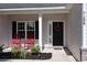 Inviting front porch featuring two red rocking chairs, a wreath on the black front door, and manicured landscaping at 206 N Levee Dr., Georgetown, SC 29440