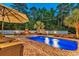 Evening view of a sparkling pool with patio furniture, an outdoor fireplace, and mature landscaping at 2441 Hunters Trail, Myrtle Beach, SC 29588