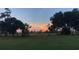 A serene view of the golf course with lush green grass and mature trees, silhouetted against a colorful sky at 290 Dornoch Dr., Pawleys Island, SC 29585