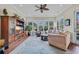 Sunroom boasts large windows, hardwood floors, a ceiling fan, and comfortable seating perfect for relaxation at 290 Dornoch Dr., Pawleys Island, SC 29585