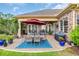 Covered outdoor patio showcasing a blue rug under an outdoor table, featuring an American flag and brick accents at 290 Dornoch Dr., Pawleys Island, SC 29585