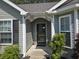 Close up of the front door with storm door, dark shutters, and nice landscaping at 3805 Mayfield Dr., Conway, SC 29526