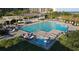 Aerial view of community pool area with lounge chairs, cabana, spa and lush greenery at 415 Ocean Creek Dr. # 2189, Myrtle Beach, SC 29572