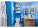 Bright blue bathroom with white toilet and wood vanity cabinet with updated faucet and lighting at 6813 Porcher Dr. # 21, Myrtle Beach, SC 29572