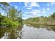 Scenic pond reflects the cloudy sky with lush trees on the bank at 6813 Porcher Dr. # 21, Myrtle Beach, SC 29572
