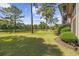 Manicured lawn leading to a tranquil pond, surrounded by lush trees on a sunny day at 69 Pinehurst Ln. # 3-F, Pawleys Island, SC 29585