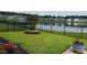 A well-maintained backyard with a black metal fence, lush green grass, a serene pond view, and manicured landscaping at 692 Cherry Blossom Dr., Murrells Inlet, SC 29576