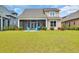 A spacious backyard with a screened porch, lush lawn, and two inviting blue chairs at 7317 Lieth Ln., Sunset Beach, NC 28468
