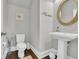 Tastefully designed powder room with a pedestal sink, round mirror, and wood-look floors at 7317 Lieth Ln., Sunset Beach, NC 28468