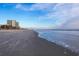 Wide beach scene with gentle waves, distant buildings, and a clear sky at 1058 Sea Mountain Hwy. # 4-203, North Myrtle Beach, SC 29582