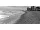 Monochrome view of the beach with gentle waves and distant buildings at 1058 Sea Mountain Hwy. # 4-203, North Myrtle Beach, SC 29582